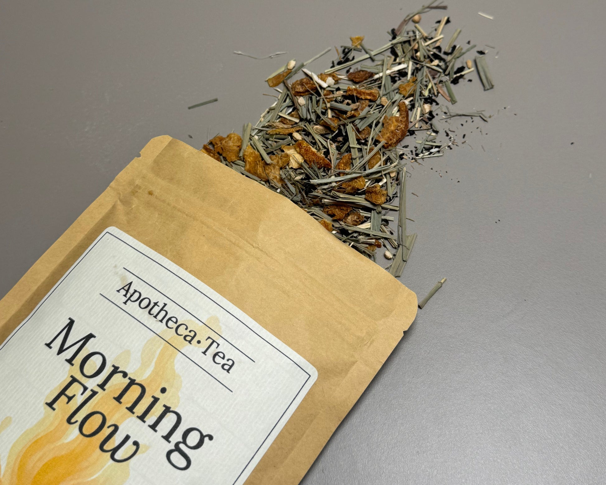 Apotheca Tea 'Morning Flow' package with loose tea leaves on a gray background