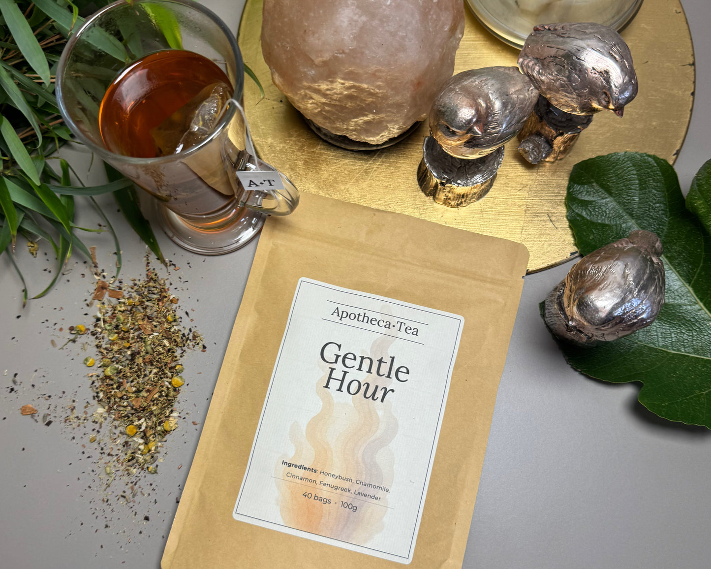 A packet of Gentle Hour tea blend form Apotheca Tea surrounded by lifestyle items such as small bird statues, himalayan salt rock and greenery.