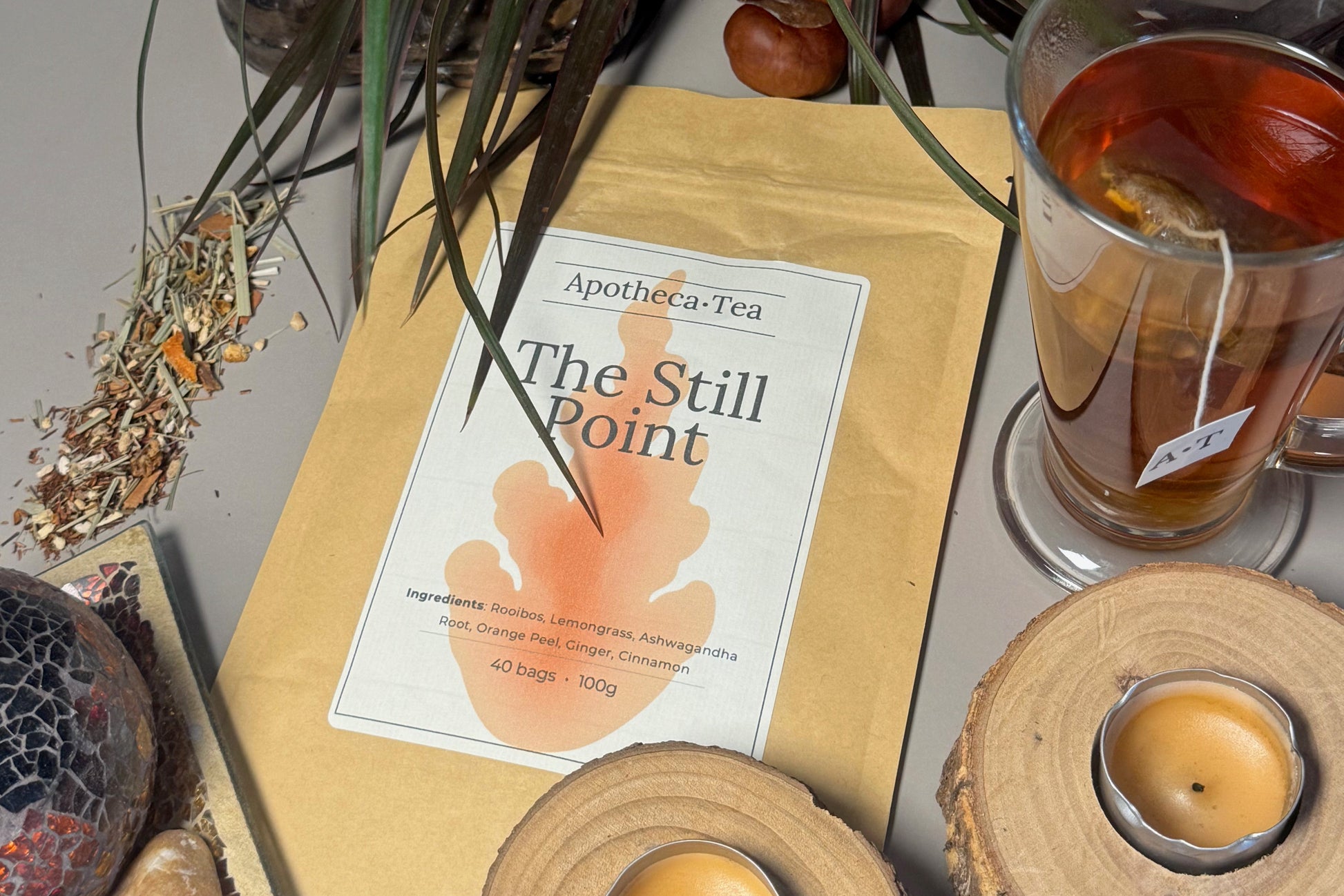 Tea packaging with a teacup, candles, and decorative items on a surface.