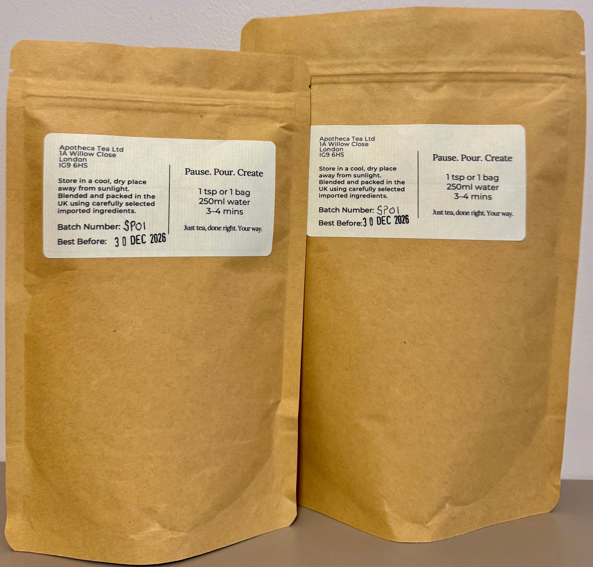 Two brown paper tea bags with labels on a gray background