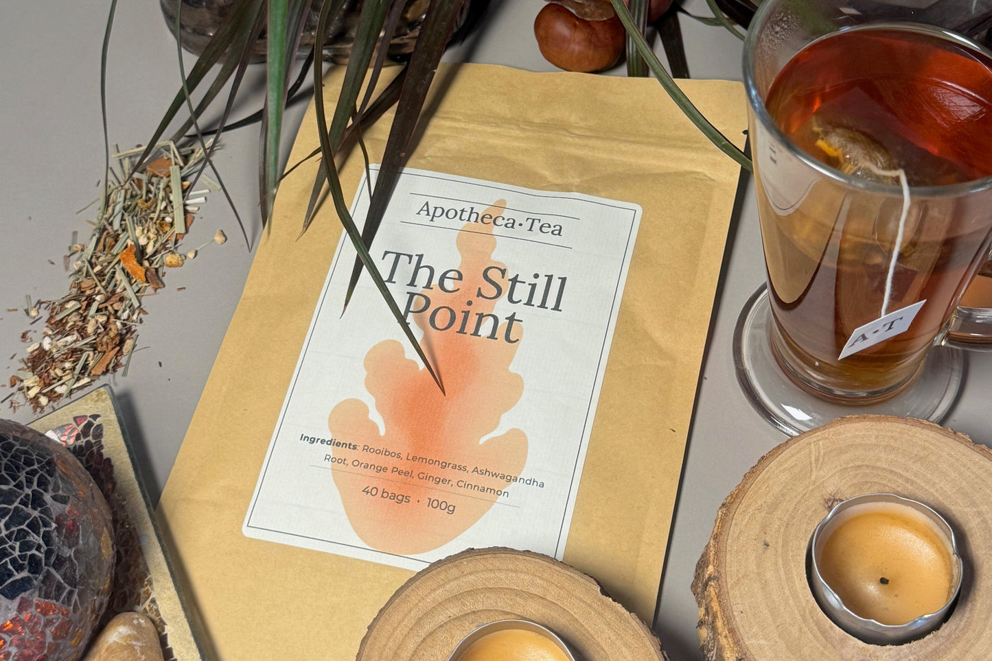 Tea packaging with a teacup, candles, and decorative items on a surface.