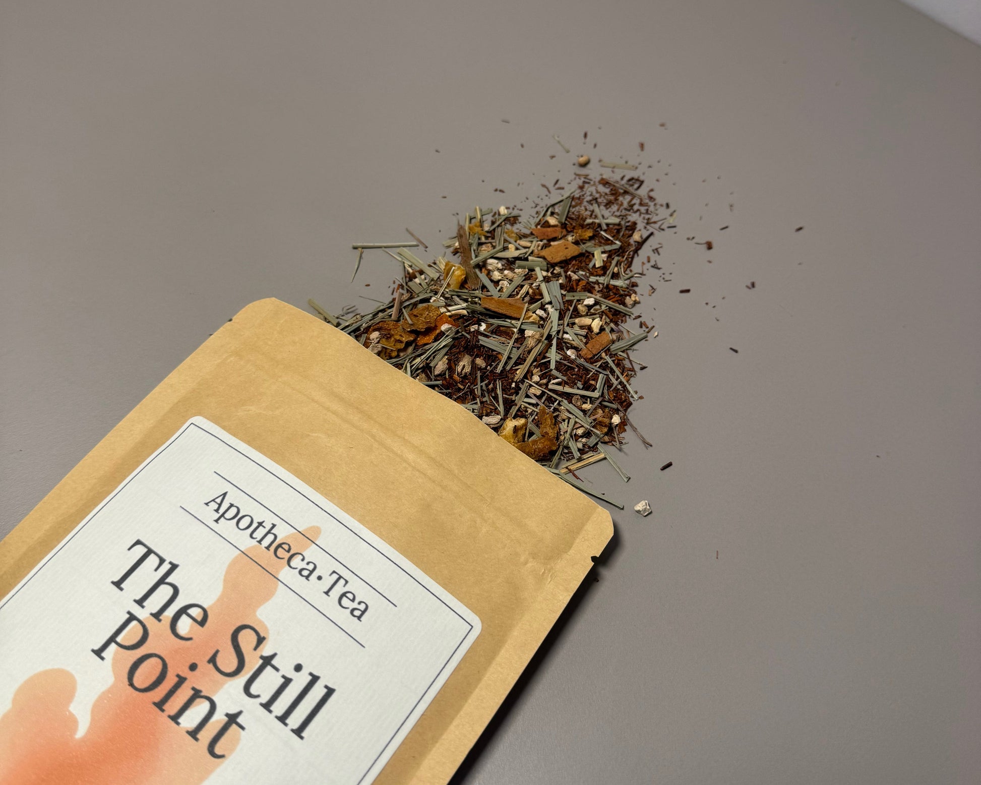 Tea packaging labeled 'The Still Point' with loose tea leaves on a gray surface