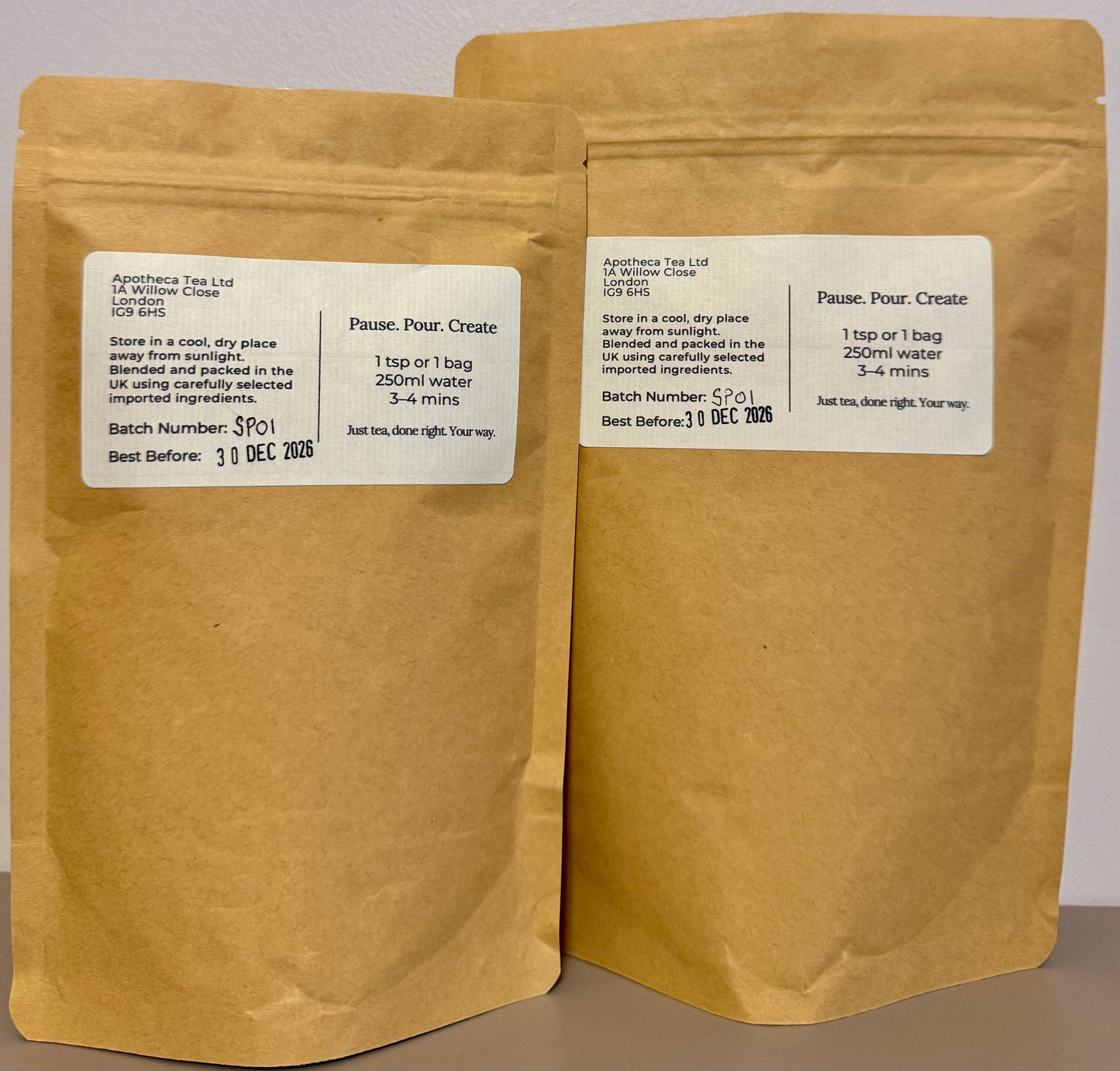 Two brown paper tea bags with labels on a gray background